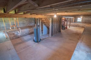 Unfinished below-ground basement with concrete floor and support beams